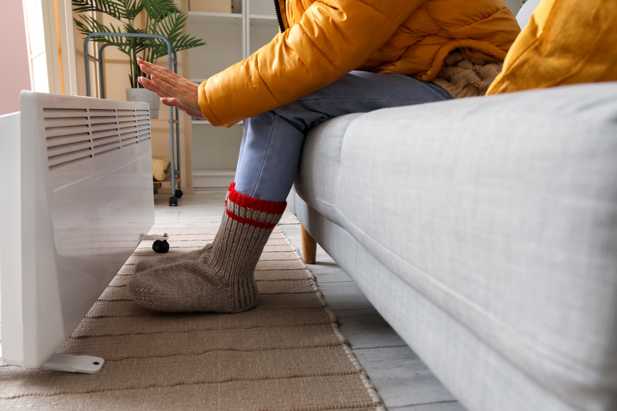 Person wärmt sich die Hände an einem Heizkörper.